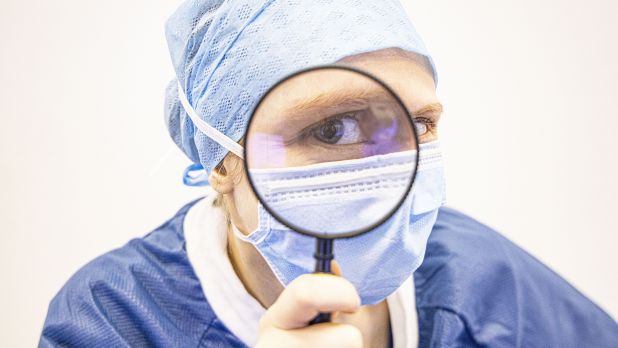 Verpleegkundige die door een vergrootglas kijkt