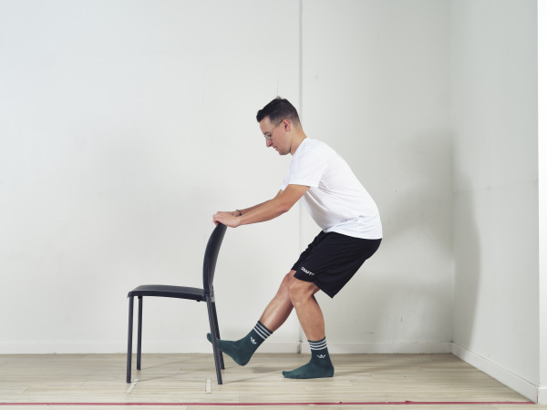 Leuning stoel vasthouden en squat doen