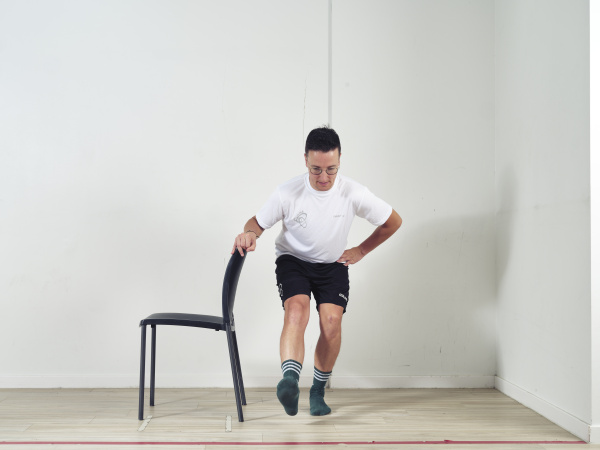 Leuning stoel vasthouden en squat doen